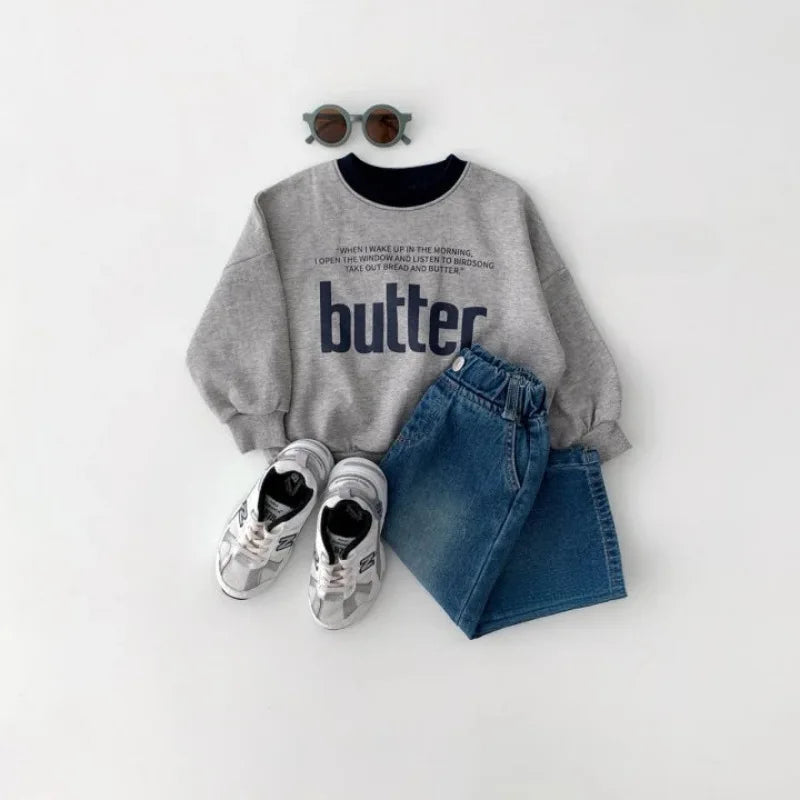 Gray sweatshirt with 'butter' text, blue jeans, and sneakers on a white background